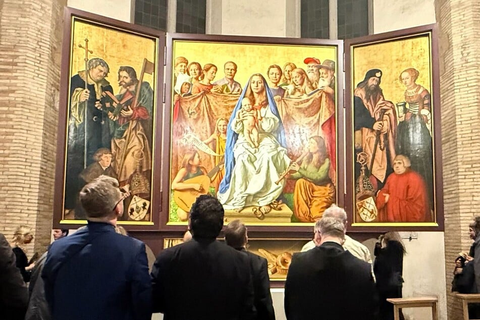 Besucher stehen andächtig vor dem Cranach-Triegel-Altar in der Marienkirche des Friedhofs Campo Santo Teutonico.