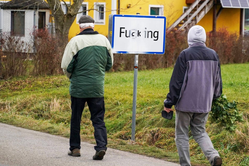 Menschen kommen an einem Ortsschild vorbei, auf dem die Buchstaben "gg" mit "ck" übermalt wurden.