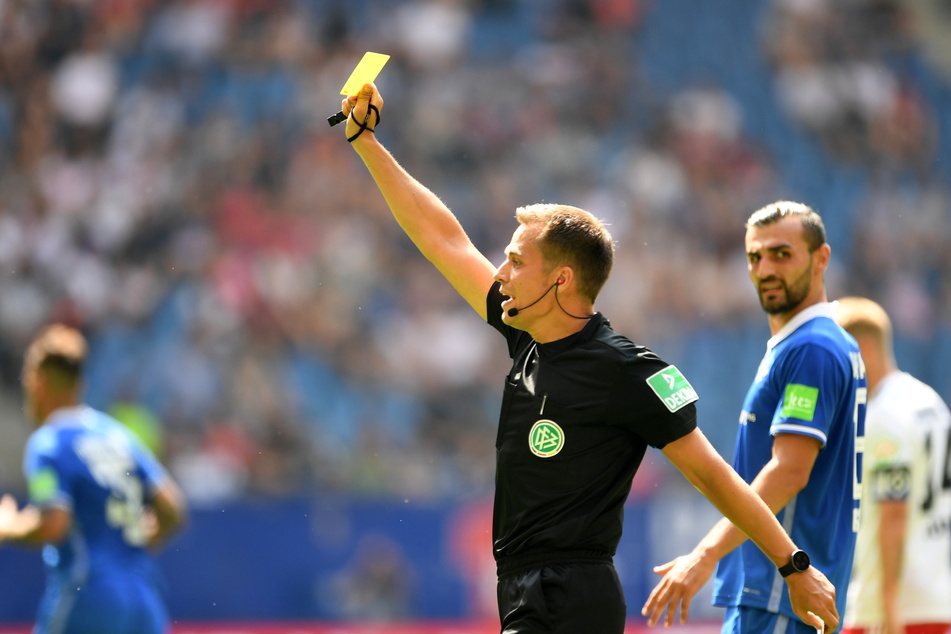 Schiedsrichter Robert Hartmann zeigt die Gelbe Karte.