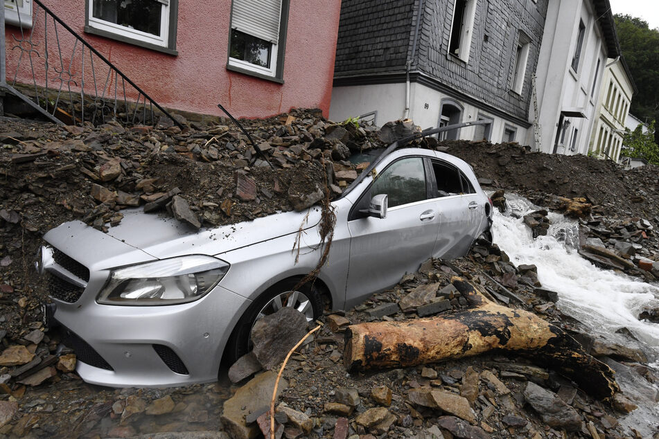 Ein Auto ist in Hagen von Schutt bedeckt, den die Überflutung des Nahmerbach am Vorabend mit sich gebracht hatte.