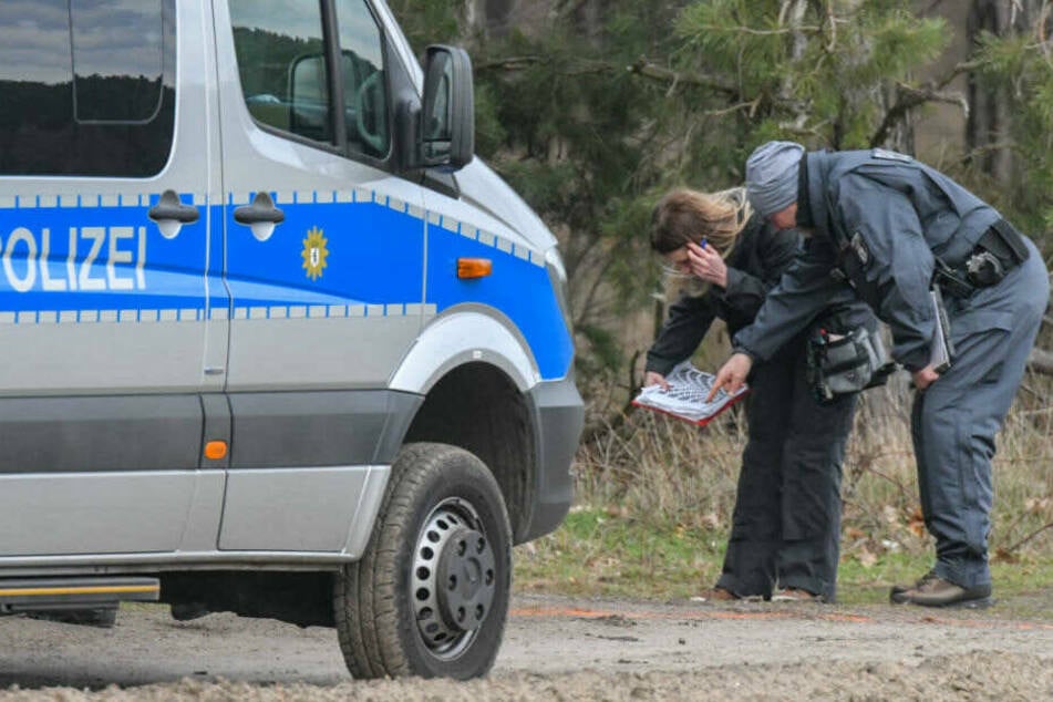Beamte der Kriminalpolizei stehen während der Suche nach der vermissten Rebecca an einem Waldgebiet im Landkreis Oder-Spree und nehmen einen Gipsabdruck einer Reifenspur.