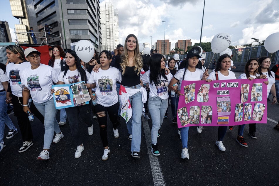 Camila Fabri Saab (c.) walks with women showing photos of children who remain in the US after being separated from their parents during a demonstration in Caracas, Venezuela, on July 10, 2025.