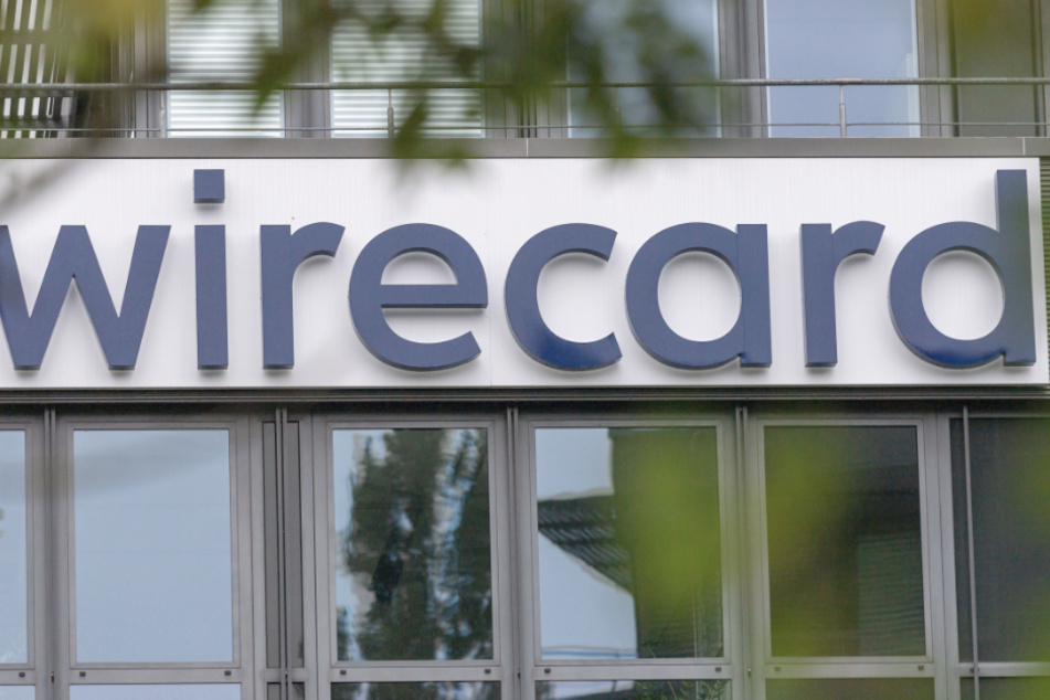 Das Logo der insolventen Firma Wirecard hängt an der Fassade des Unternehmens in Aschheim bei München. Nun wurde ein Mitarbeiter von der Bafin angezeigt.