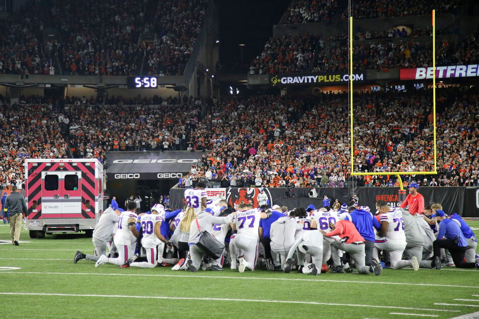 Buffalo Bills players and staff huddle on the field after Damar Hamlin suffered a cardiac arrest.