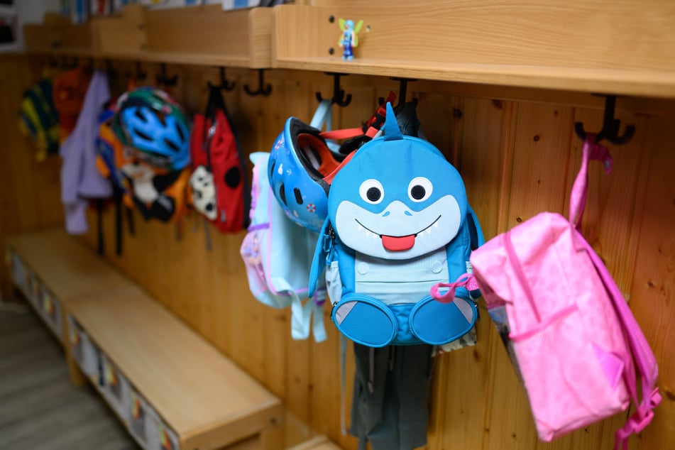 Kinderrucksäcke hängen in der Garderobe einer Kita. (Symbolfoto)