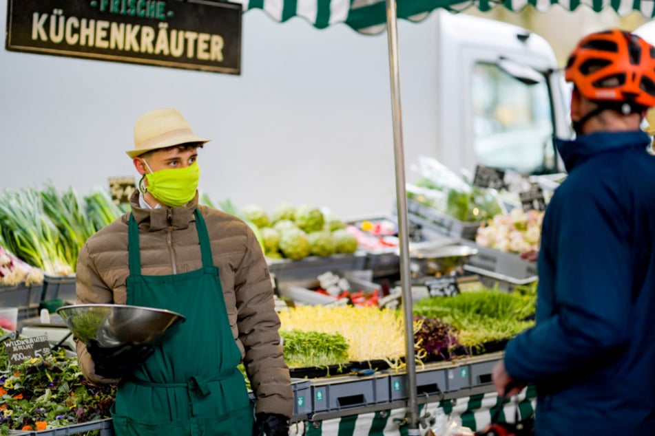  Ein Mitarbeiter bedient mit einem Mundschutz die Kunden auf dem Isemarkt.