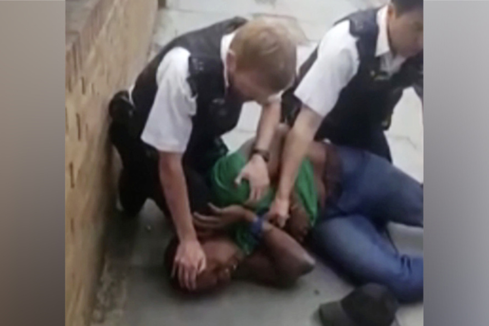 Ein Polizist drückt einem schwarzen Mann sein Knie auf den Hals.