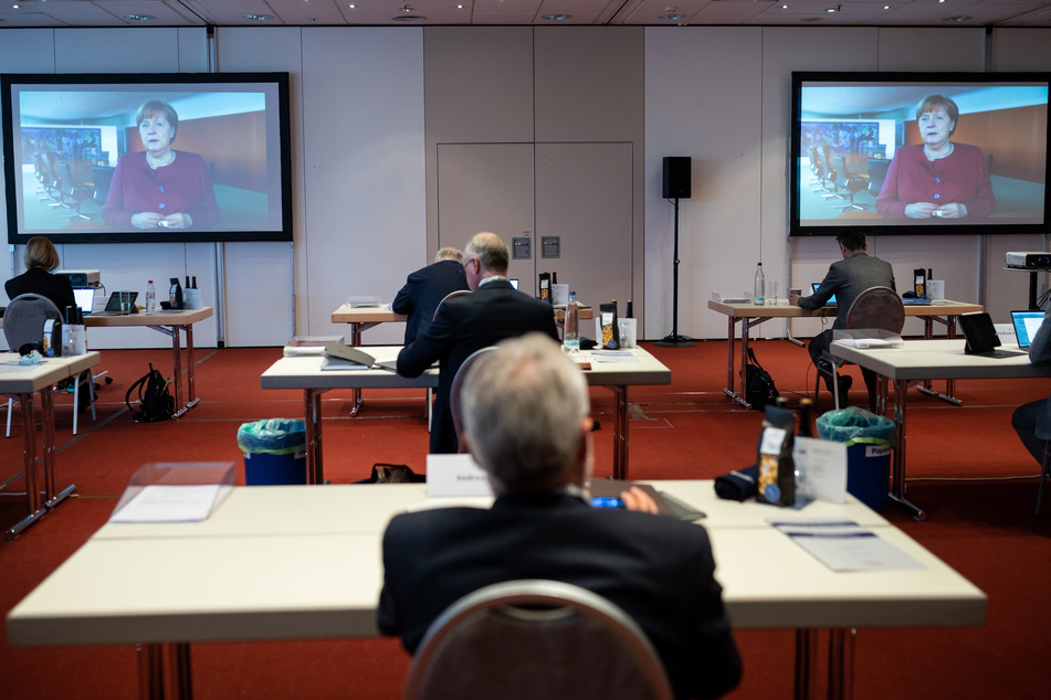 Teilnehmer des 124. Deutschen Ärztetages, der zum größten Teil rein digital stattfindet, verfolgen das Grußwort von Bundeskanzlerin Angela Merkel.