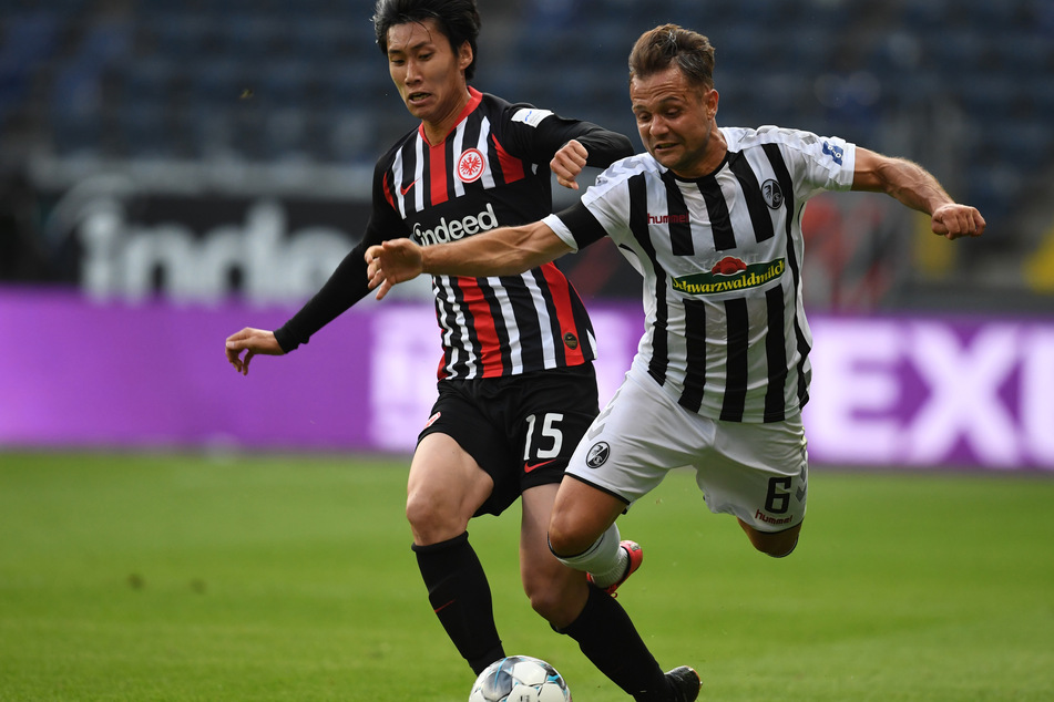 Daichi Kamada (l.) von Eintracht Frankfurt versucht den Ball gegen Freiburgs Amir Abrashi zu behaupten.