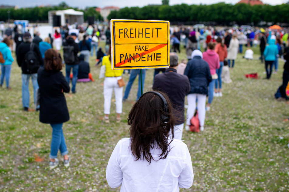 Eine Teilnehmerin einer Demonstration gegen die Anti-Corona-Maßnahmen steht im Mai 2020 auf der Theresienwiese und hält ein Schild mit der Aufschrift "Freiheit / Fake Pandemie" in den Händen.
