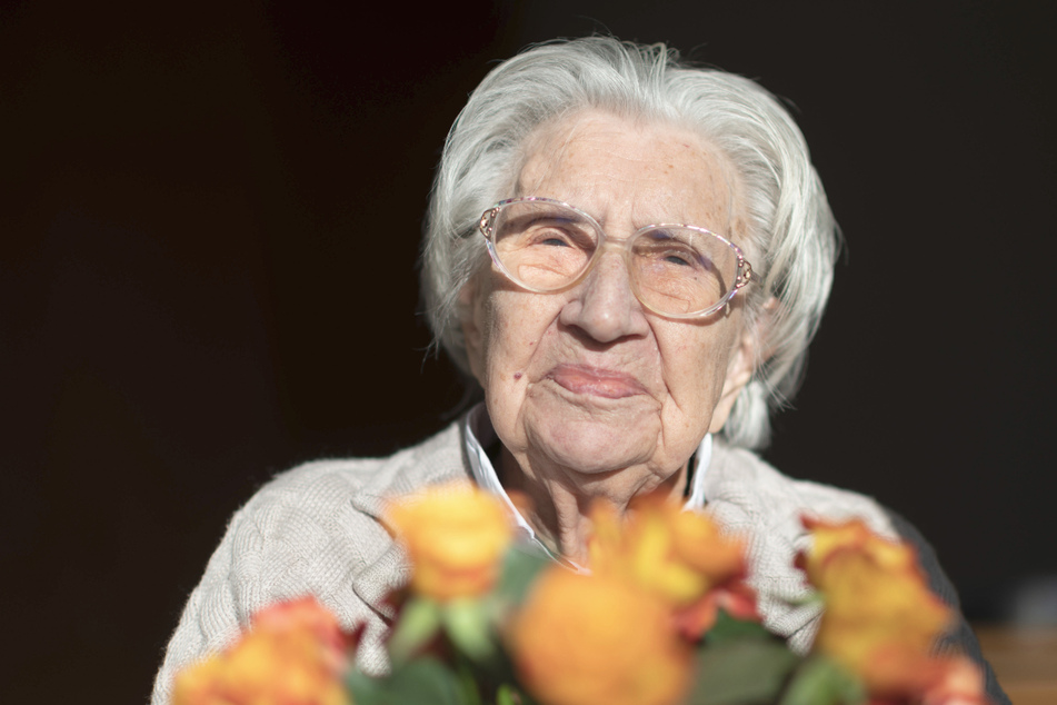 Mina Hehn hat an ihrem 108. Geburtstag in ihrem Terasseneingang in einem Pflegeheim einen Blumenstrauß auf dem Schoß.