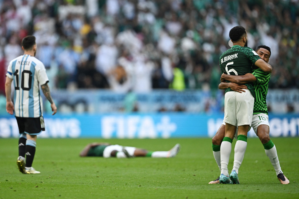 Lionel Messi (l.) looks on as Saudi Arabian players celebrate at full time.