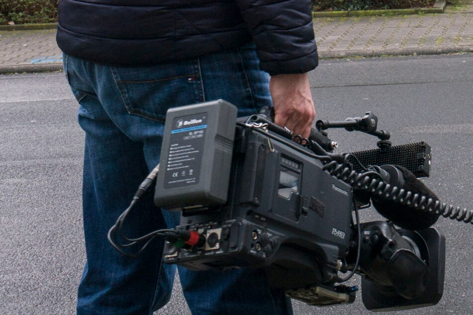 Ein Reporter hält eine Kamera in der Hand.