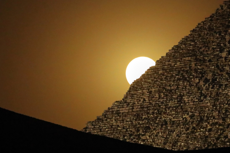 Der Vollmond leuchtet hinter der Großen Pyramide von Gizeh, der Cheops-Pyramide.