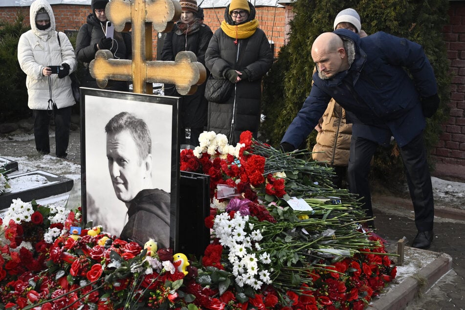 A man lays flowers at the grave of Russian opposition leader Alexei Navalny at the Borisovo cemetery in Moscow on February 16, 2025, marking the first anniversary of his death in an Arctic colony under murky circumstances.