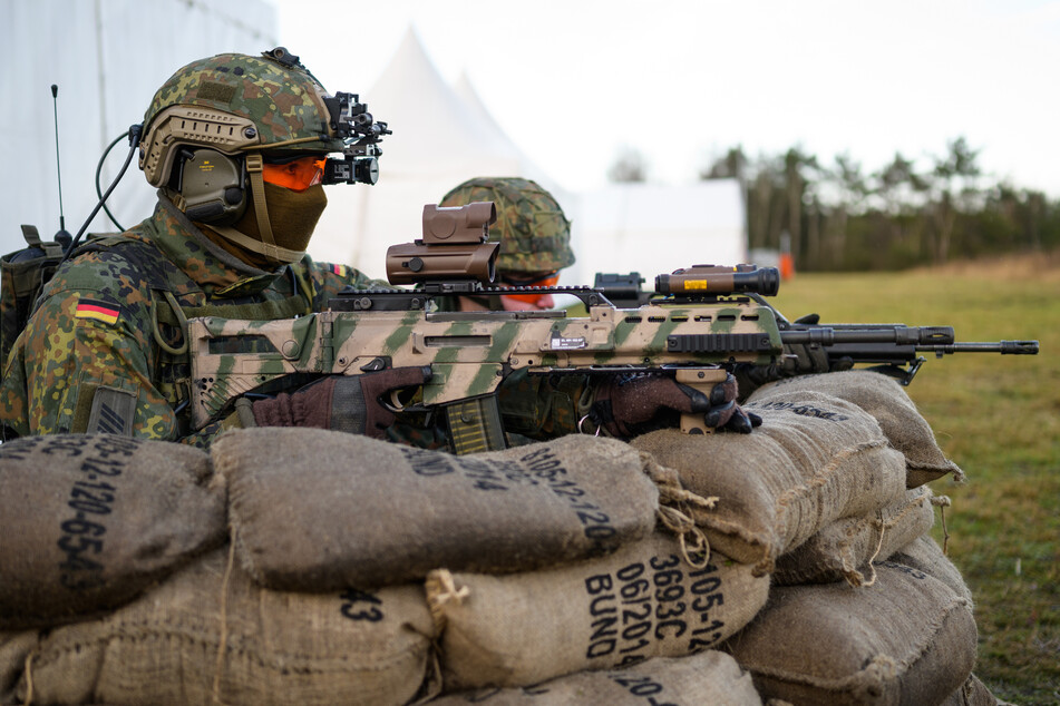 Soldaten der Bundeswehr haben mit dem Sturmgewehr vom Typ G36 A2 während einer Vorführung in Munster hinter Sandsäcken Stellung bezogen.
