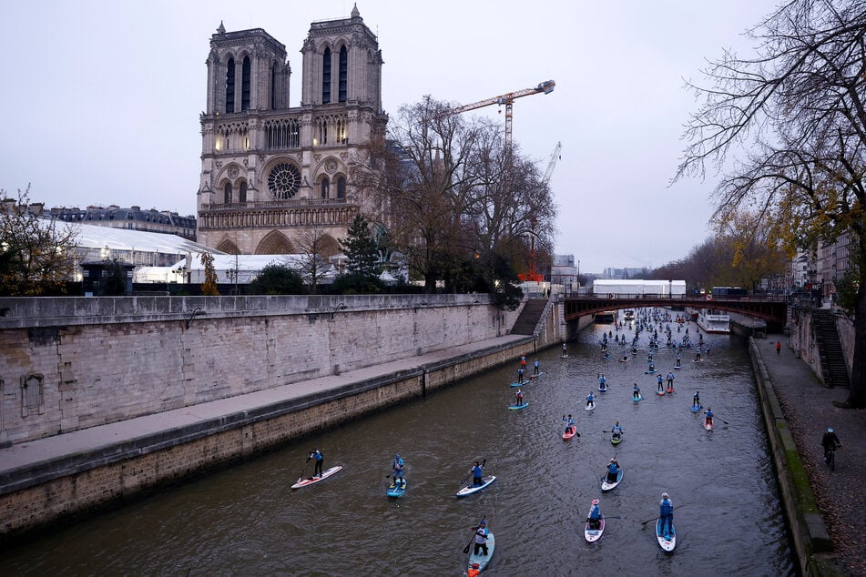 Participants make their way past the Notre-Dame Cathedral as they attend the 13th edition of the stand up Nautic Paddle race on the river Seine in Paris, France, December 1, 2024.