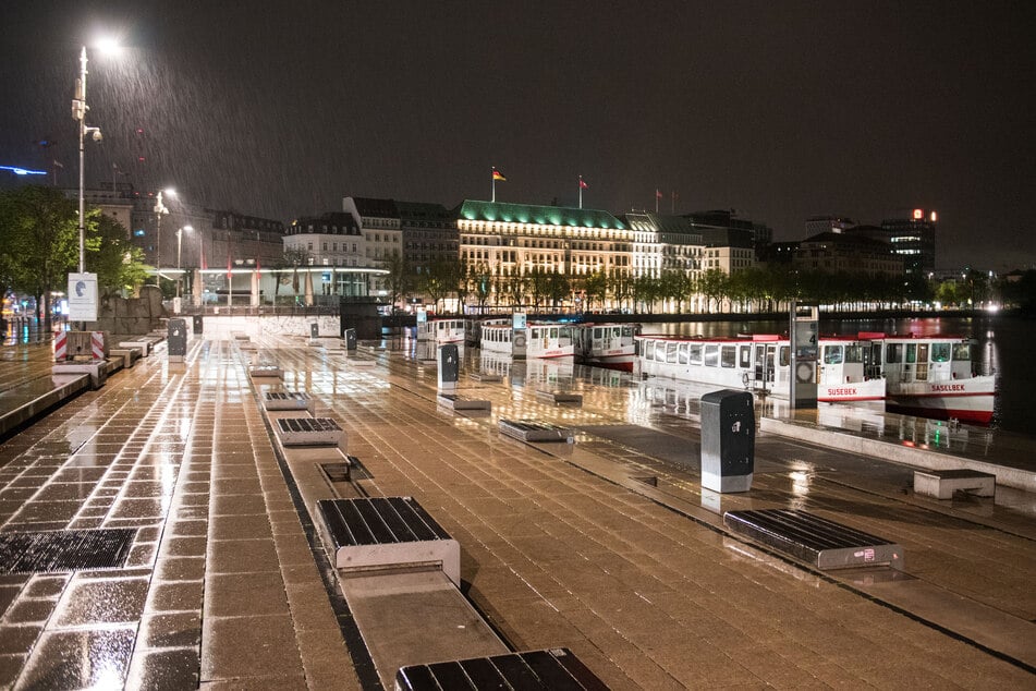 Der Jungfernstieg ist kurz nach 0 Uhr bei Regen menschenleer. Seit Mitternacht ist die wegen der Coronapandemie geltende Ausgangssperre aufgehoben.