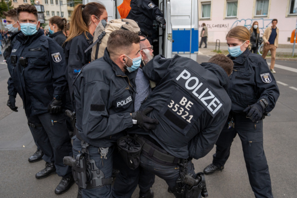 Polizisten nehmen am Rande eines Corona-Protests in Berlin einen Demonstranten fest.
