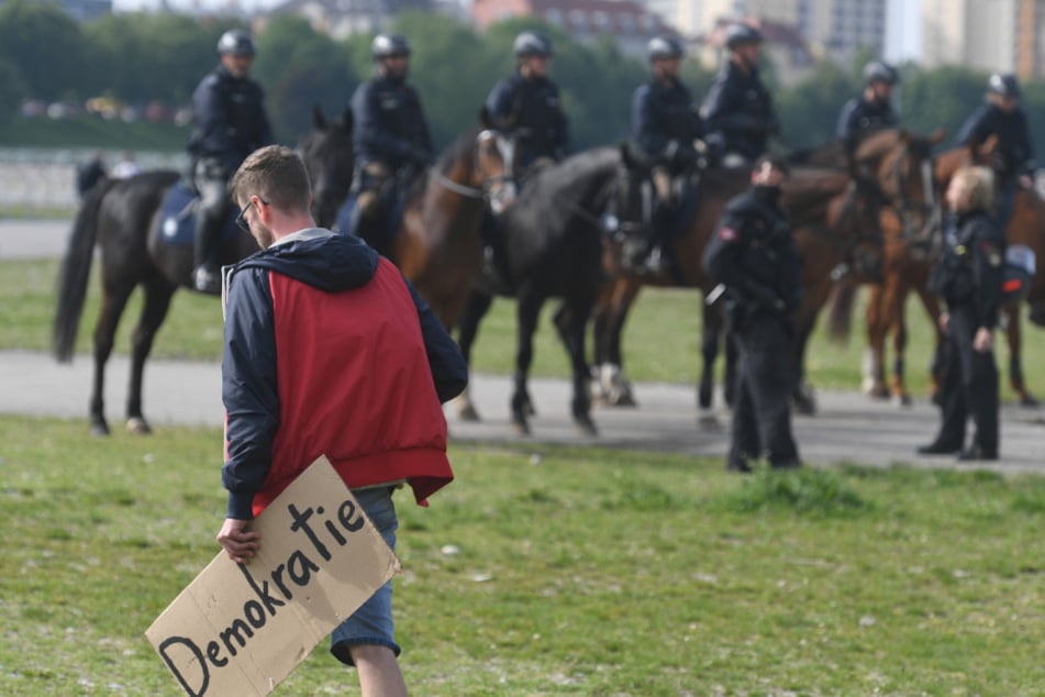 Ein Demo-Teilnehmer geht auf der Theresienwiese an berittener Polizei vorbei.