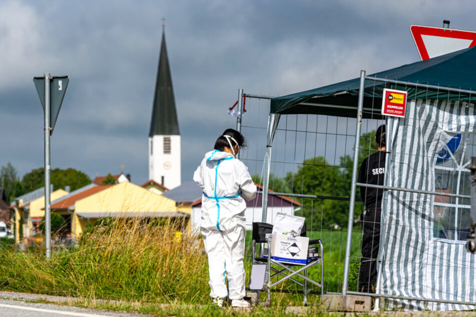 Eine Frau in Schutzkleidung steht nahe eines Bauernhofs. Nach der Corona-Masseninfektion Erntehelfern auf einem Gemüsehof in Mamming will die Staatsregierung am Montag eine Covid-Teststation in der niederbayerischen Gemeinde aufbauen.