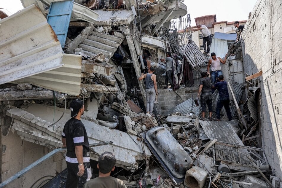 Palestinian men gather outside a collapsed building as they attempt to rescue survivors from underneath the rubble following Israeli bombardment in Jabalia in the northern Gaza Strip.