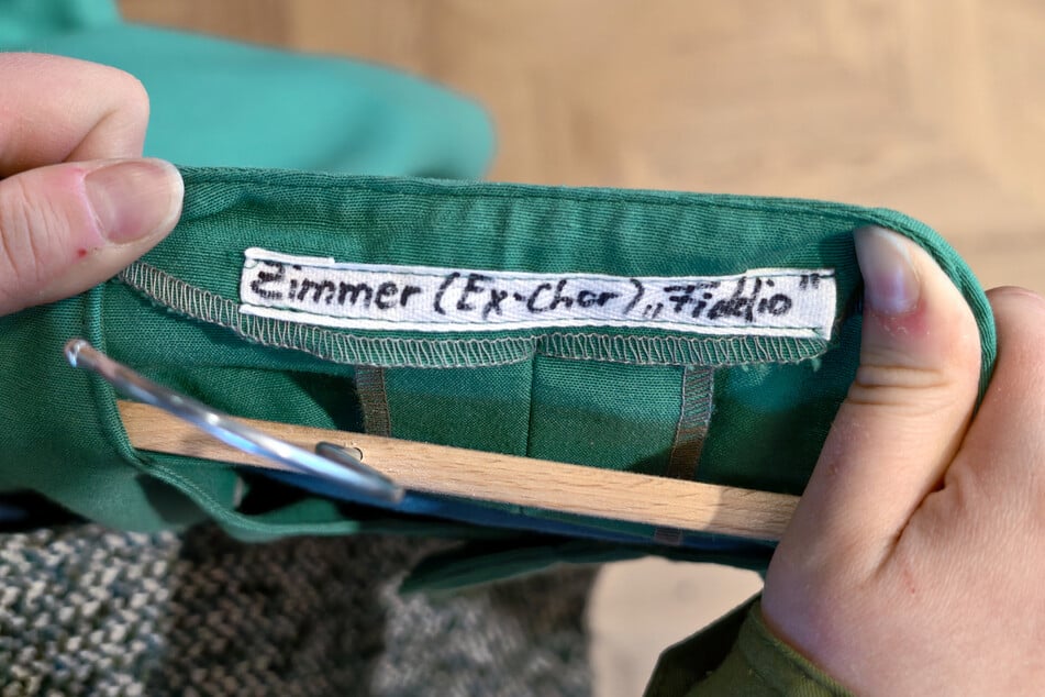 In der Kleidung stehen der Name des Darstellers und das Stück.