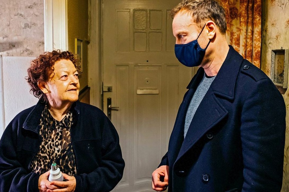 Kriminalhauptkommissar Robert Karow befragt Mieterin Ilse Kirschner (Friederike Frerichs, 77). Die Ermittlungen finden unter Corona-Bedingungen statt, weshalb die Kommissare eine Maske tragen und Abstand halten.