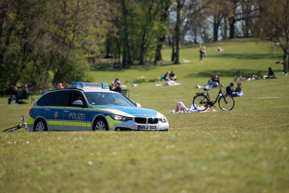 Ein Polizeiwagen fährt am Sonntag bei Sonnenschein durch einen Park am Aachener Weiher. (Symbolbild)