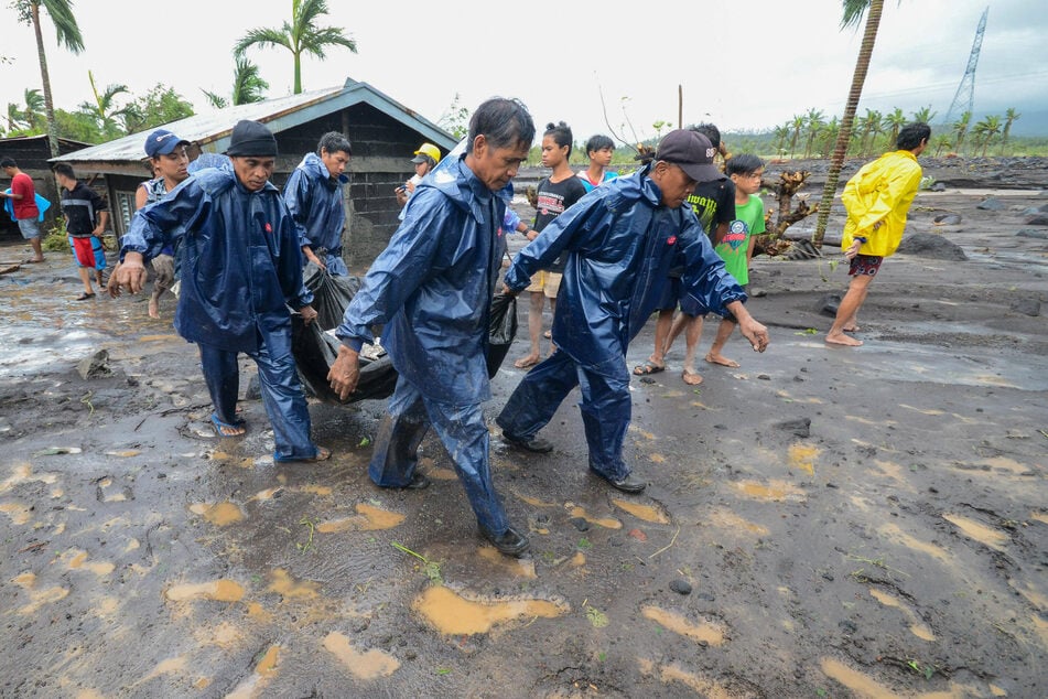 Emergency responders carry the body of a person who was buried in mud after a flood brought by the heavy rains from typhoon Goni in Albay Province, the Philippines.