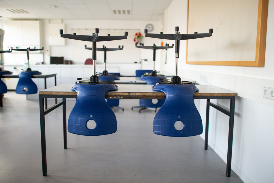 Stühle stehen in einem leeren Klassenzimmer auf den Tischen, da der Unterricht in der Corona-Zeit ausgefallen ist.