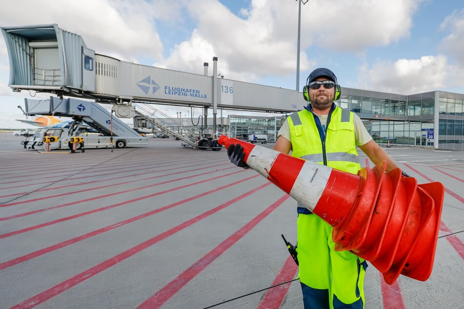 Hilft dem Flugzeug später, rückwärts auszuparken: Pushback-Fahrer Marcel Hammer (36) trägt Verkehrskegel zum Absperren aufs Rollfeld.