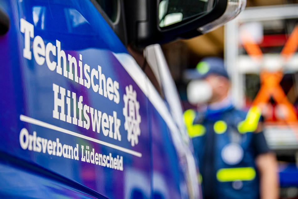 Ein Wagen des Technischen Hilfswerks (THW) steht vor einer Flugzeughalle.