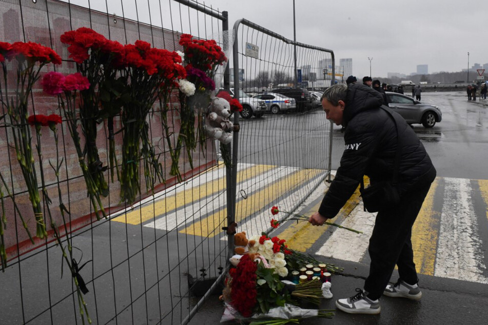 Ein Mann legt an einer behelfsmäßigen Gedenkstätte Blumen für die Opfer des Anschlags nieder.