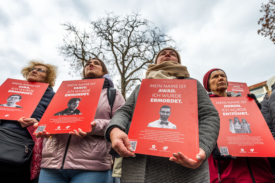 Teilnehmer der Gedenkveranstaltung auf dem Stephanplatz halten Schilder mit Porträts von israelischen Bürgern, die durch Mitglieder der Hamas umgebracht wurden.