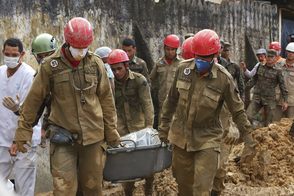 Feuerwehrleute und Soldaten bergen die Leiche eines Opfers einer Schlammlawine.