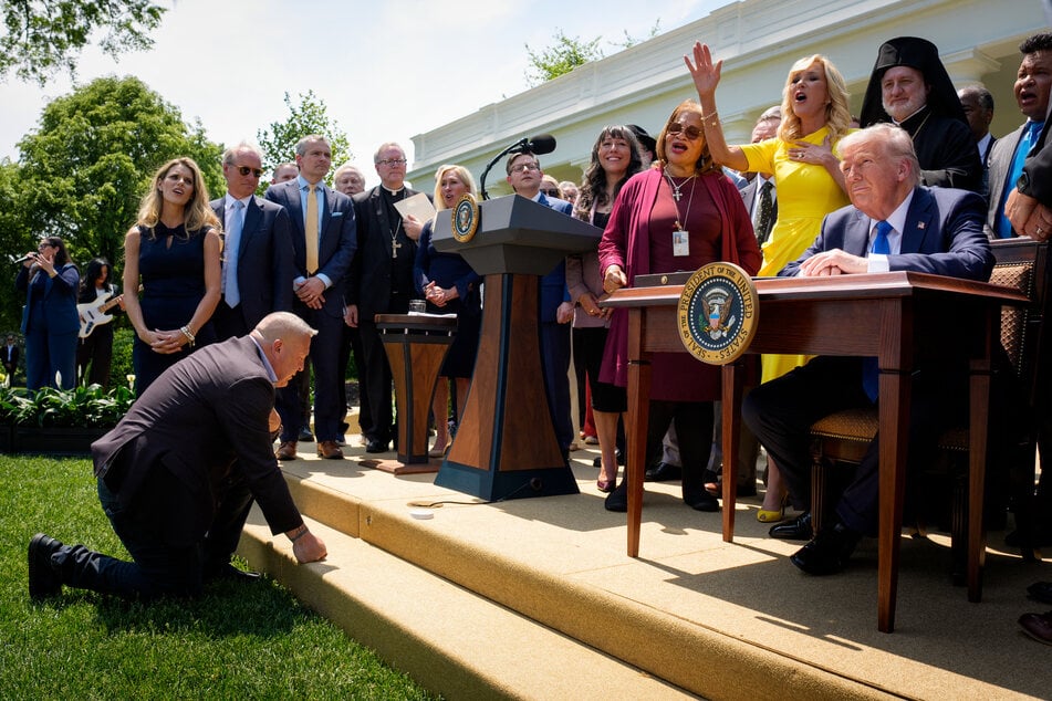 Head of the White House Faith Office Paula White-Cain (in yellow) sings as she and other religious leaders stand next to President Donald Trump during a National Day of Prayer event at the White House on May 1, 2025.