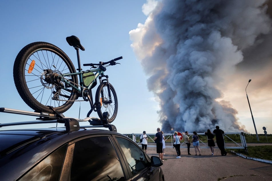 Onlookers watch as smoke rises from an e-commerce form in Russia that was hit by Ukrainian drones on July 18, 2026.