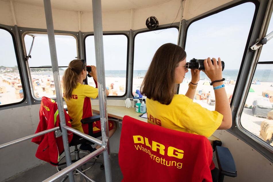DLRG-Rettungsschwimmerinnen beobachten auf einem Wachturm den Strand und das Wasser in Travemünde.