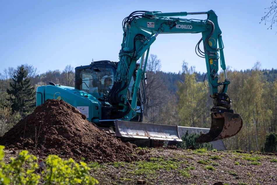 Im Kurpark wird per Bagger Erde für die neuen Rabatten verteilt.