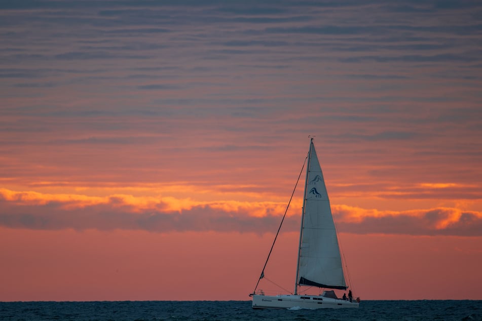 Ein Segelboot ist vor Sonnenaufgang auf der Ostsee unterwegs. Für Urlauber aus Mecklenburg-Vorpommern können Hotels und Ferienwohnungen wieder öffnen.