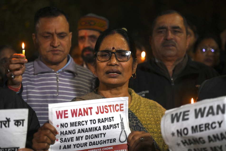 Asha Devi, Mutter des Opfers der Gruppenvergewaltigung von 2012, hält zusammen mit anderen Menschen Kerzen und Plakate hoch.