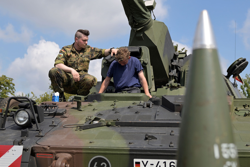 Ein Besucher beim "Tag der Bundeswehr 2023" in Brandenburg/Havel steigt aus einem Leopard 2 Panzer aus. Ein Soldat hilft ihm dabei.
