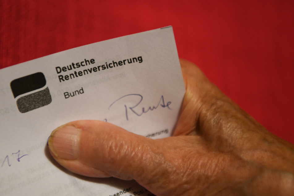 Eine Rentnerin hält ihren Rentenbescheid in der Hand.