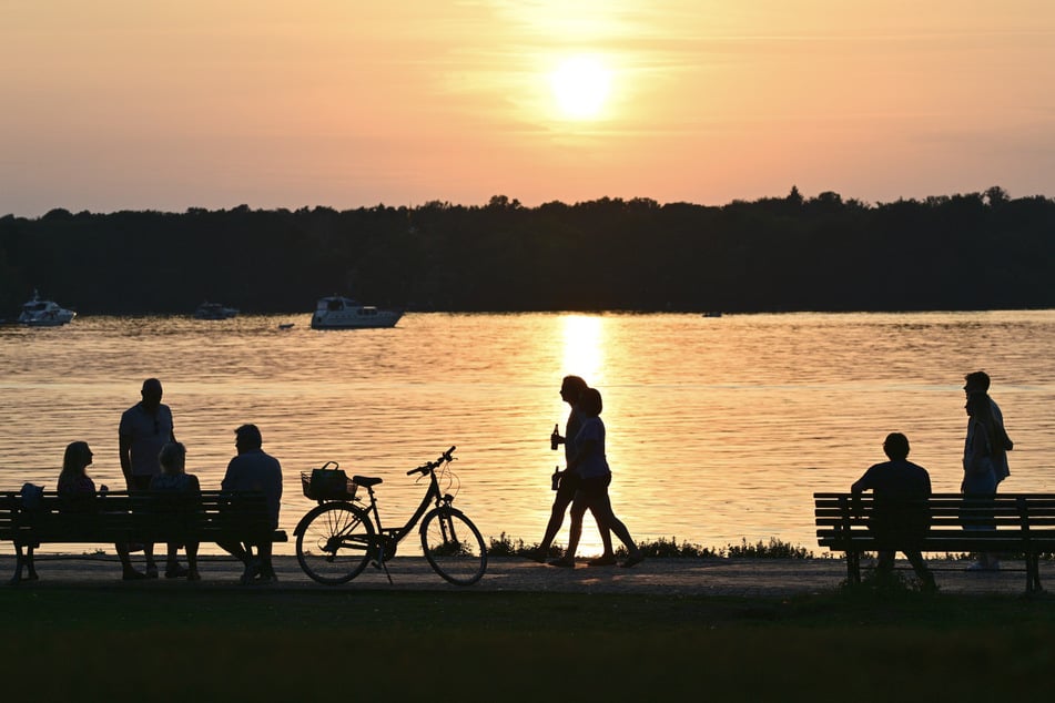 Berliner genießen am Tegeler See den Sonnenuntergang.