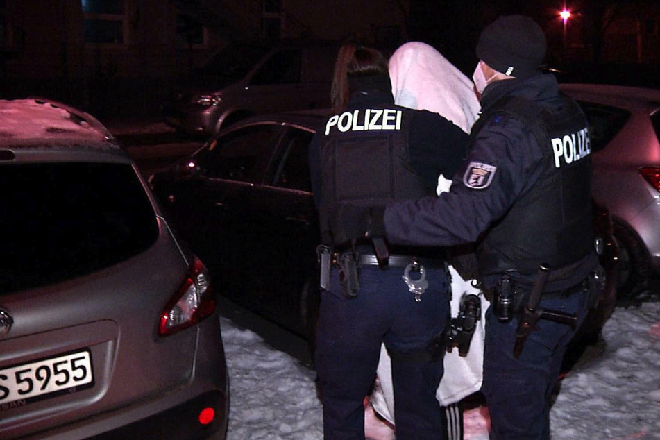 Die Polizei führt einen 23-Jährigen ab, der an der Tat beteiligt gewesen sein soll.
