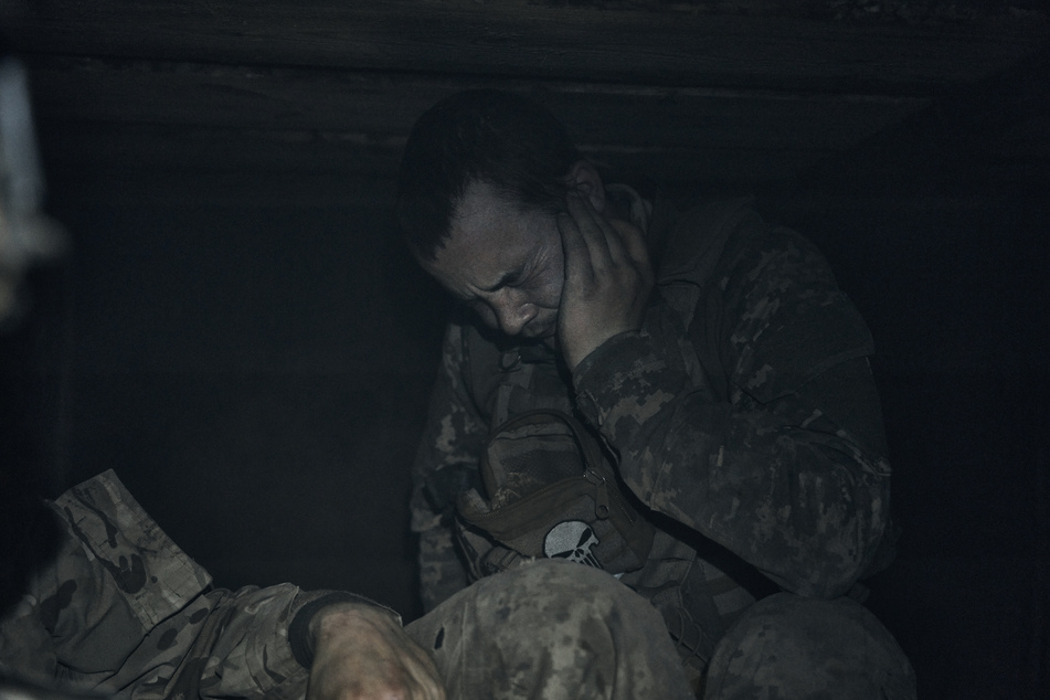 Ein ukrainischer Soldat hält sich in einem Unterstand die Ohren zu, während des russischen Beschuss an der Frontlinie in Bachmut.