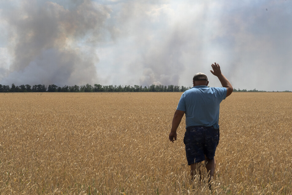 Ein Landwirt reagiert, als er auf sein brennendes Feld blickt, verursacht durch die Kämpfe an der Frontlinie in der Region Dnipropetrowsk.