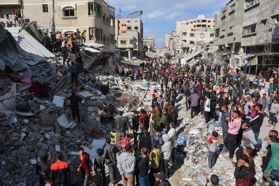 People gather around the rubble of a house destroyed in an Israeli strike as rescuers search for casualties on al-Jalaa street in central Gaza City on November 18, 2024.