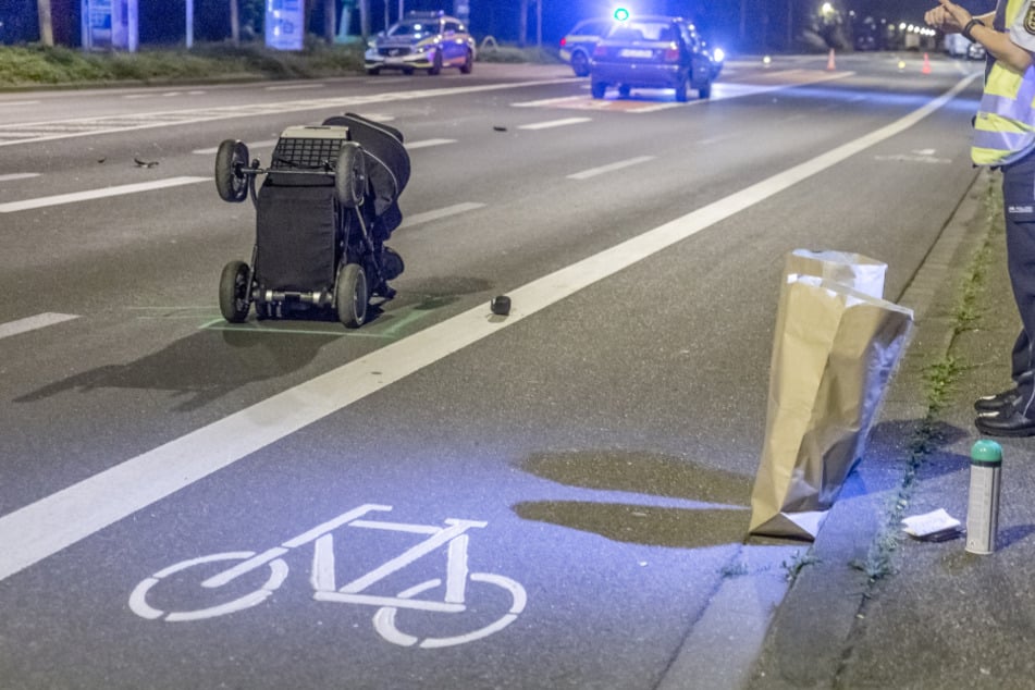 Der Kinderwagen liegt auf der Straße.